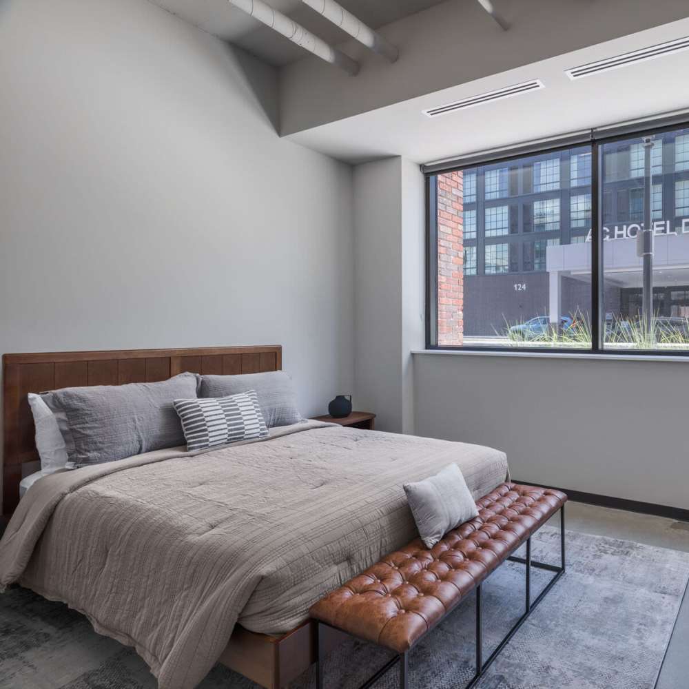 A cozy bed in a bedroom of the apartment home at The Delco in Dayton, Ohio
