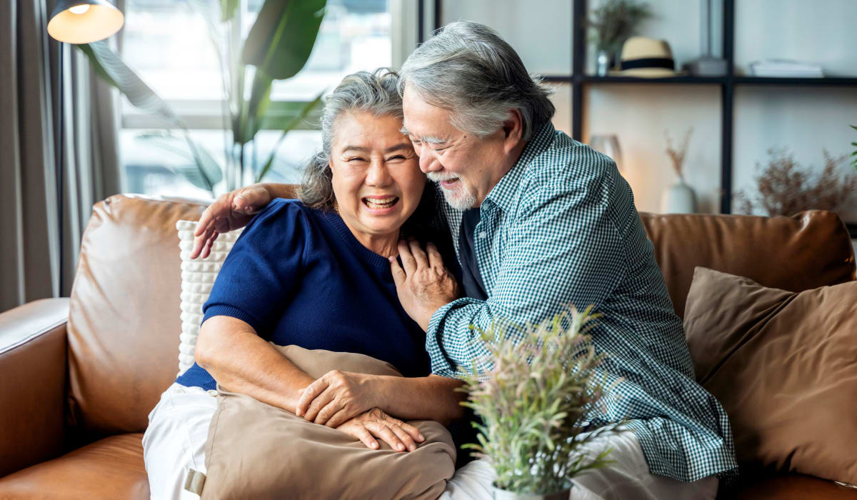 A happy couple hugs on the sofa in their apartment at Attain at Quarterpath, Williamsburg, Virginia