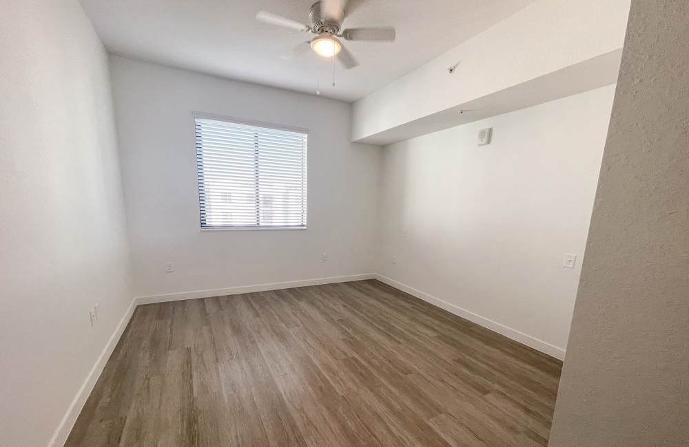 Bedroom with ceiling fan, large window and wood-style flooring at Park Apartments in Homestead, Florida