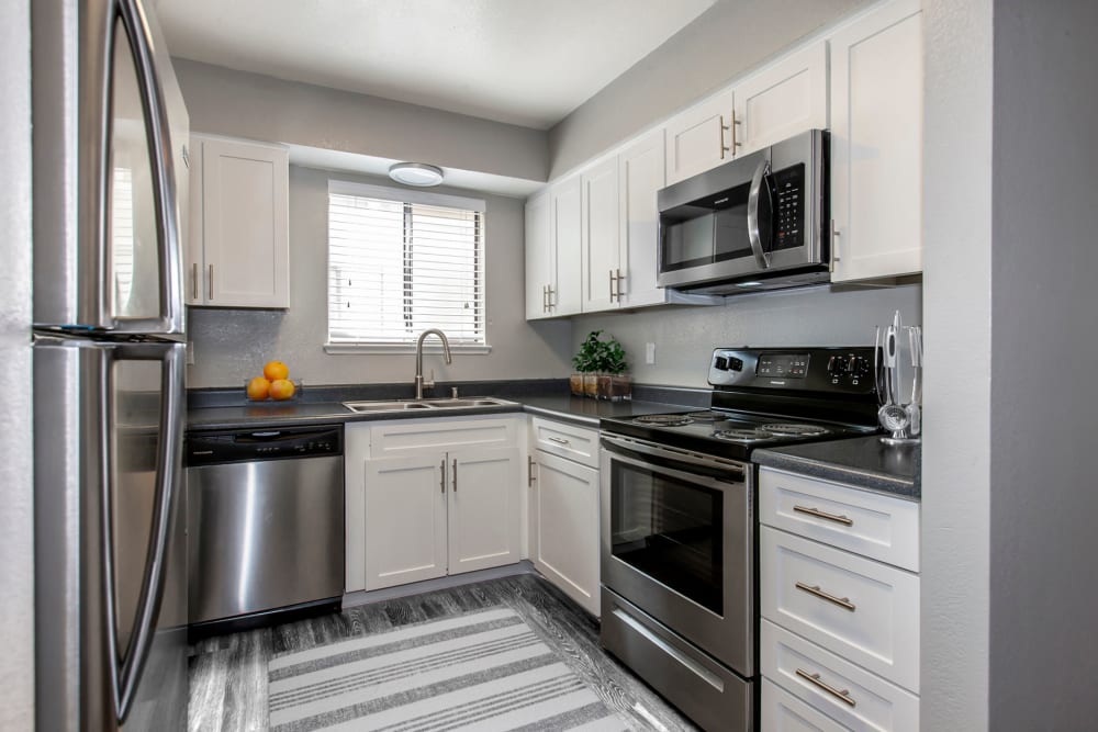 Modern kitchen with white cabinets and stainless steel appliances at Bennington Apartments in Fairfield, California