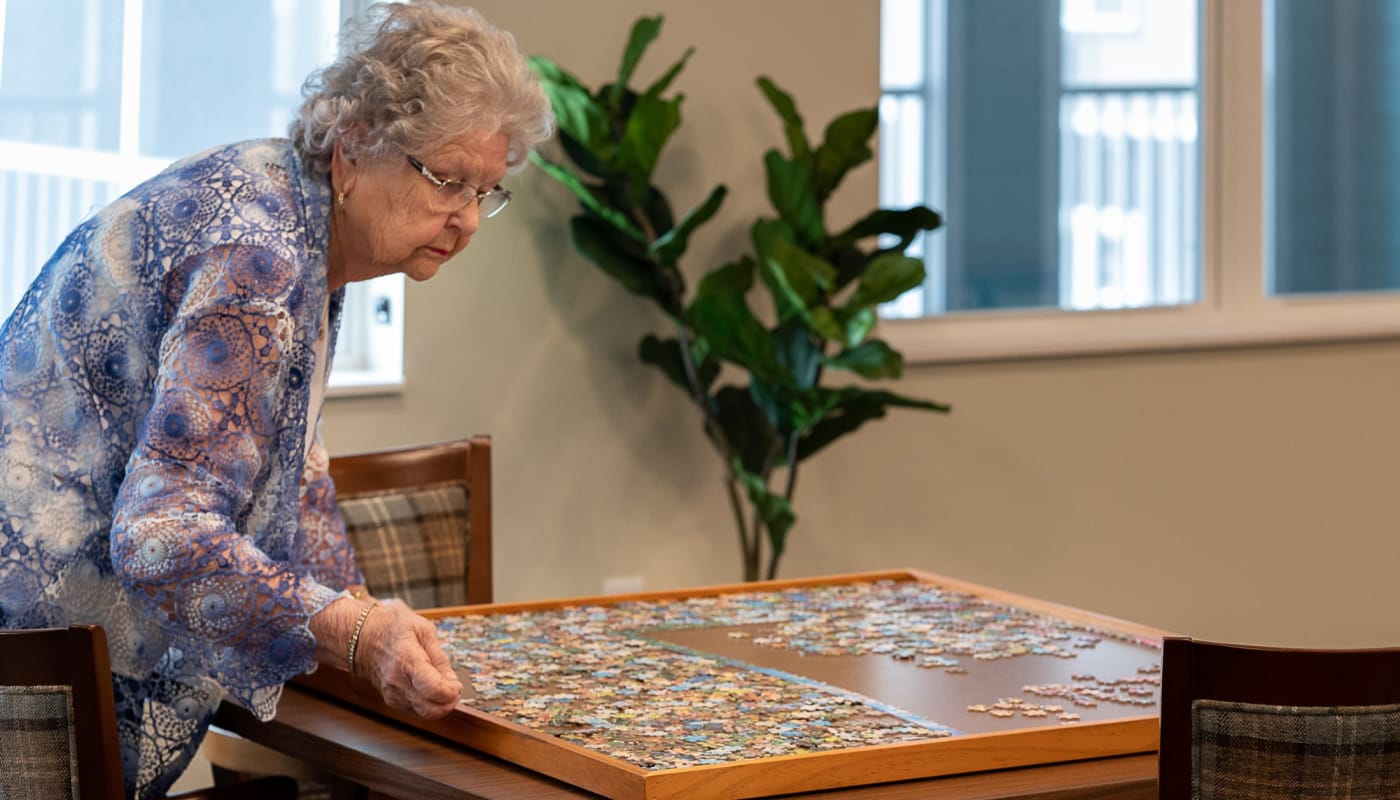 Senior woman working on a jigsaw puzzle at The Pillars of Grand Rapids in Grand Rapids, Minnesota