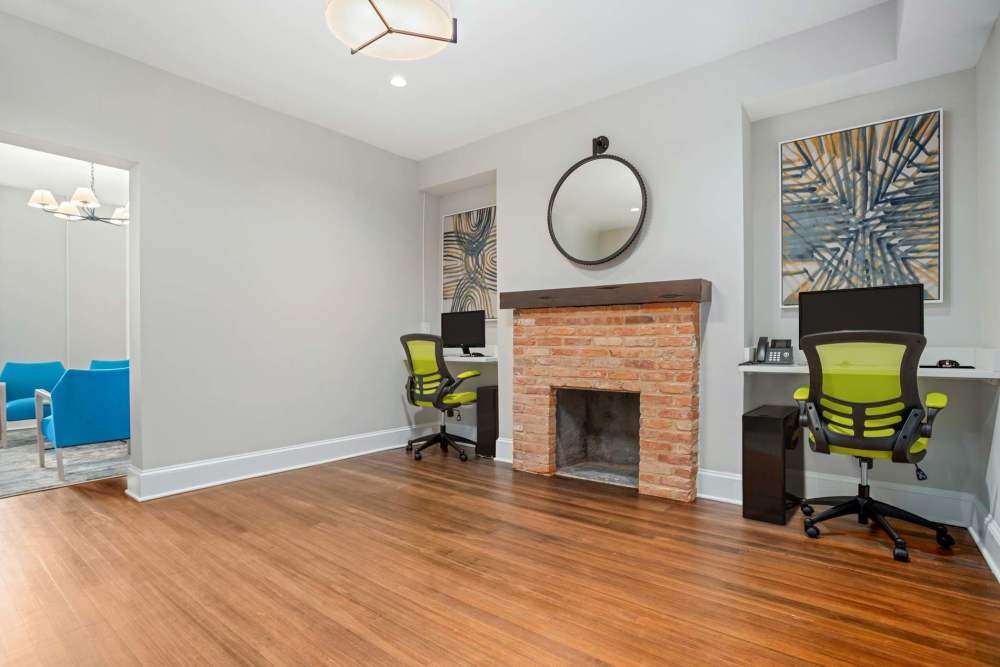 Open layout with wood-style flooring, brick fireplace, and two workstations with vibrant chairs at Crestwood Manor in Frederick, Maryland