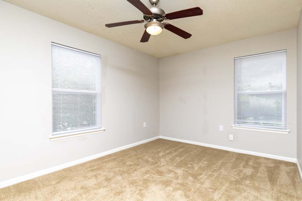 Unfurnished bedroom with ceiling fan and windows at West Village Apartments in Hillsborough, North Carolina