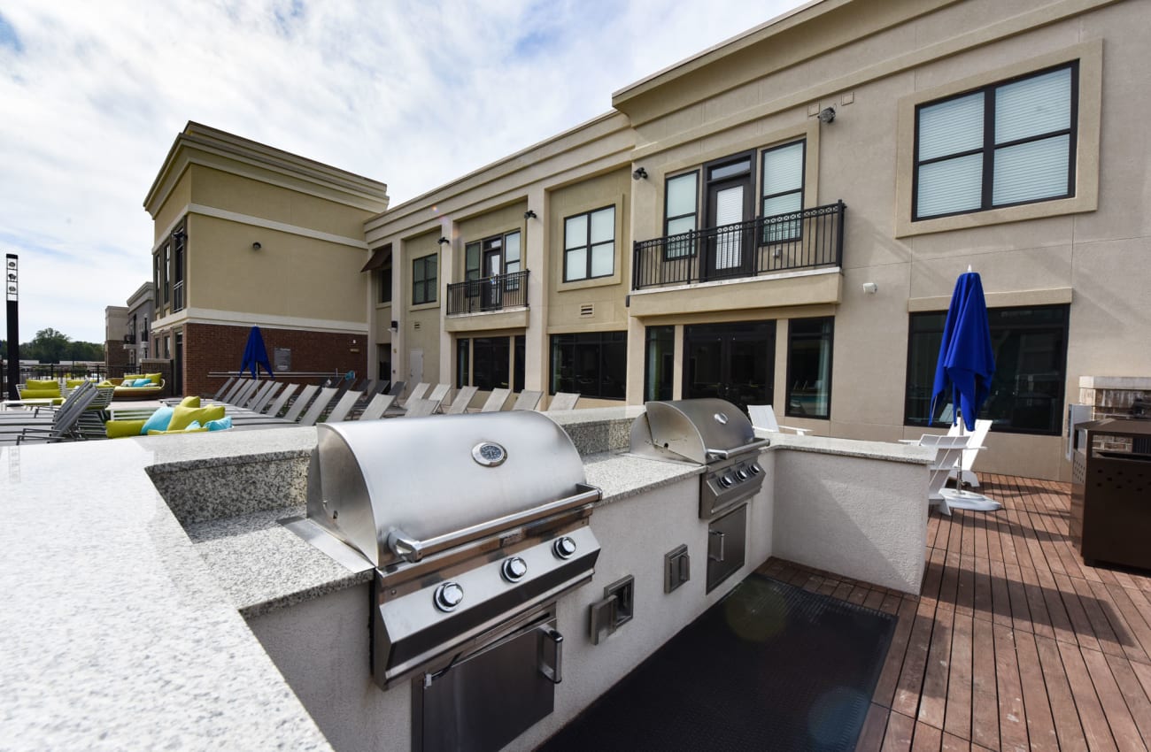 Pet-Friendly Apartments in Alpharetta, GA -The Haven at Avalon - Poolside Grill Area with Two BBQs, Granite-Style Countertops, and Seating.