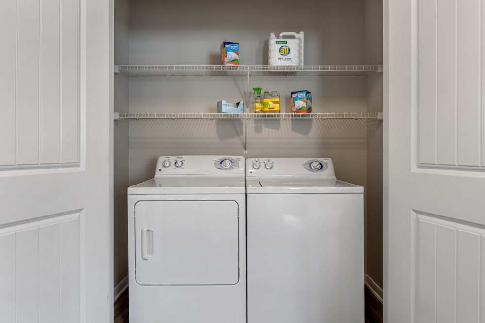 Laundry closet with full size washer and dryer and shelves at Marquis at Sugar Land in Sugar Land, Texas