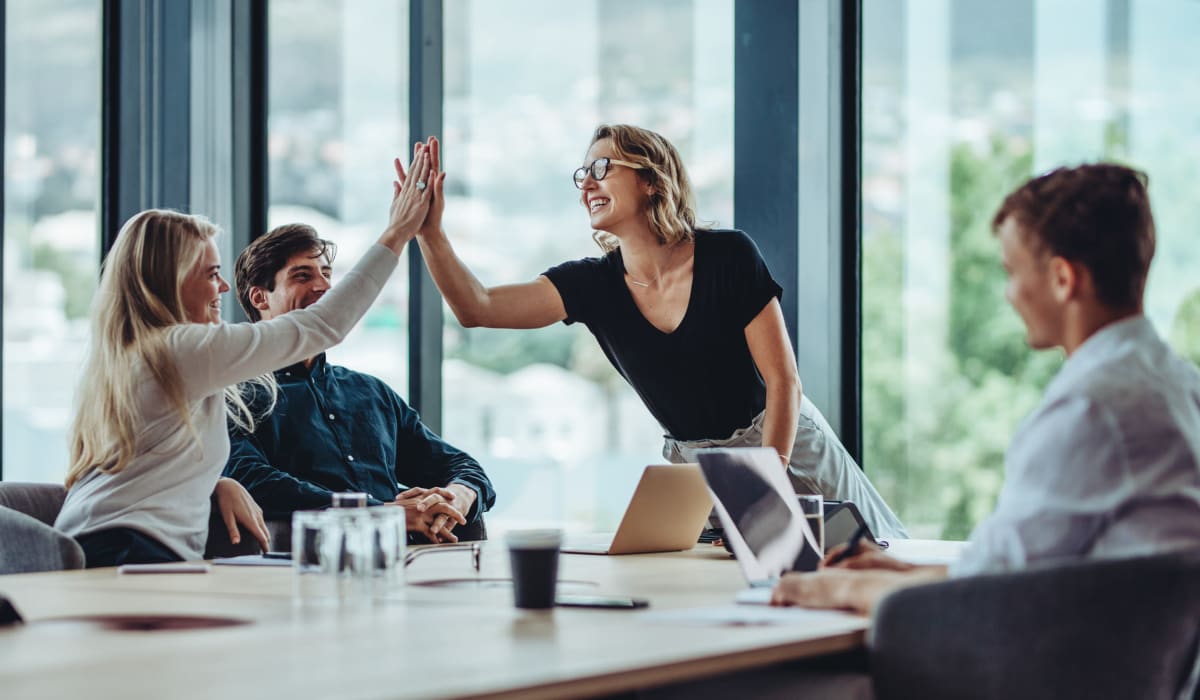  Team mates high five at a successful meating Decron Properties, Los Angeles, California