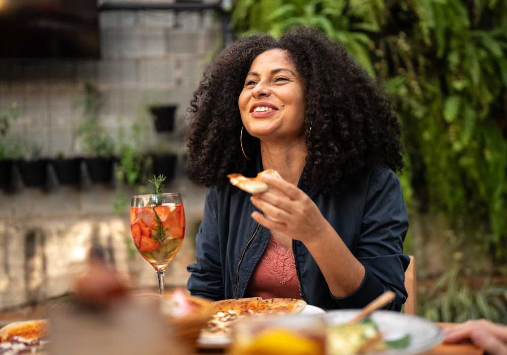 Woman enjoying pizza and drink at outdoor table Oak Creek in New Braunfels, Texas
