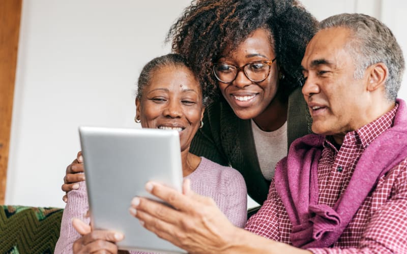 Resident couple using a tablet computer with assistance from a younger family member at Blossom Collection in Rochester, Michigan