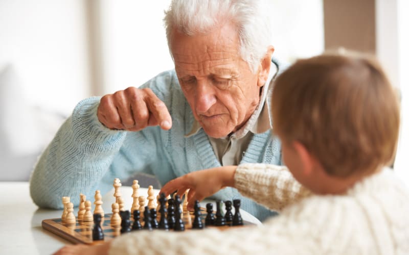 Young boy playing chess with his grandfather at Grand Villa of Deerfield Beach in Deerfield Beach, Florida