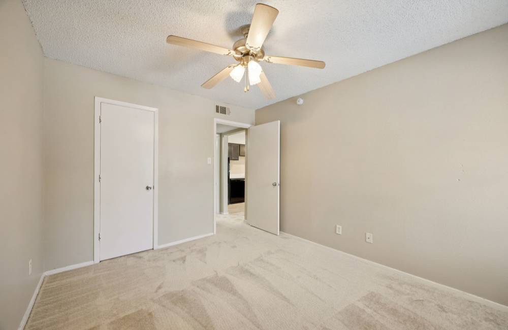 Bedroom with ceiling fan at Shadow Brook Apartments in Arlington, Texas