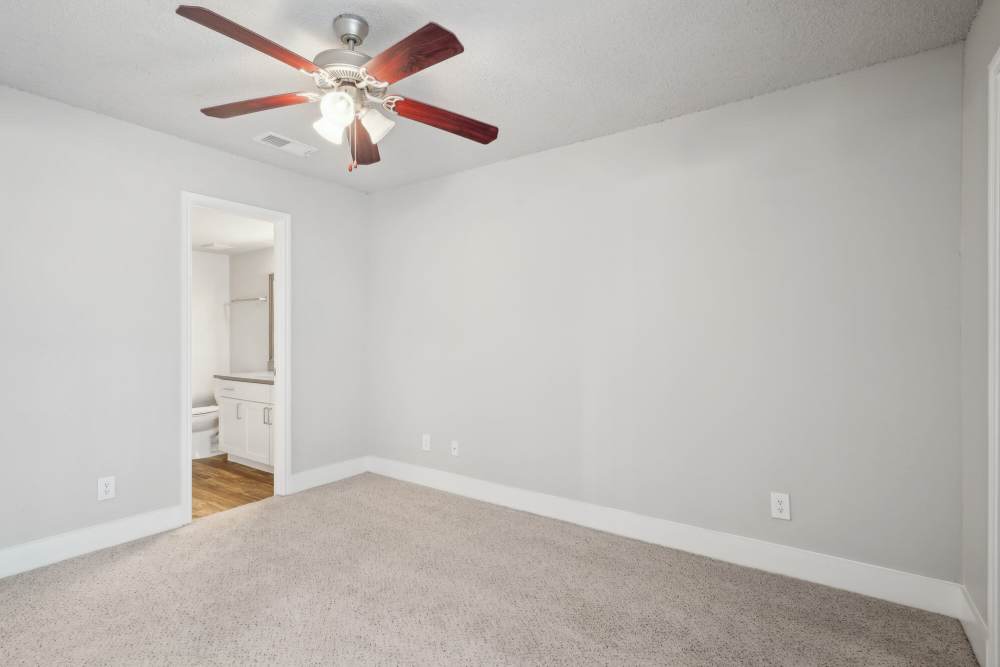 Unfurnished bedroom with ceiling fan and attached bathroom at Halston in Dallas, Texas