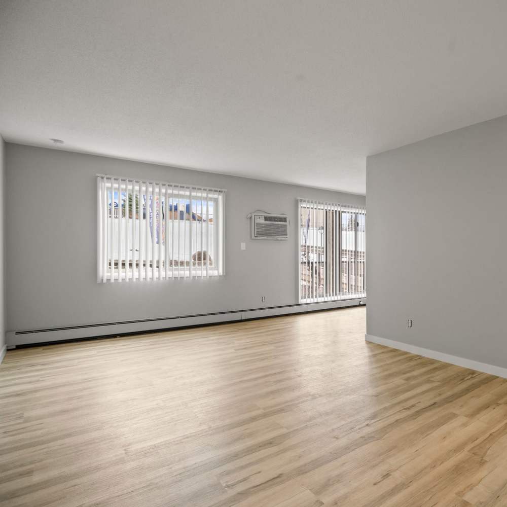 Wood-style floored living room with vertical curtain blinds to windows at Morada in Crystal, Minnesota
