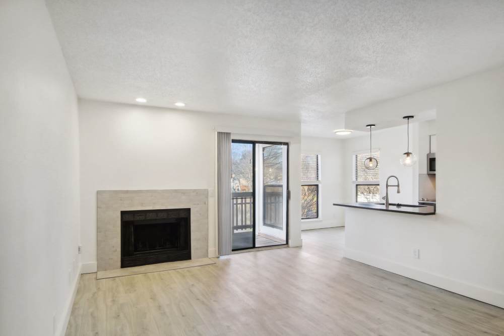 Unfurnished living room with fireplace, wood-style flooring and access to private balcony at Stillwater in Charlotte, North Carolina