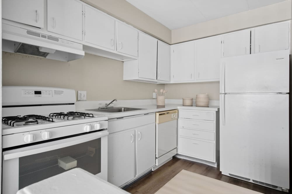 Modern kitchen with white cabinetry, gas stove, and ample counter space at Granada Gardens Apartments in Warrensville Heights, Ohio