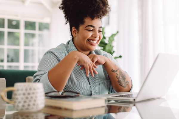 Smiling woman with curly hair using a laptop near Dakota at Hillcroft in Houston, Texas