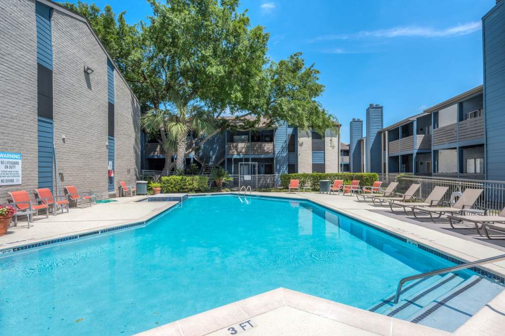 Outdoor swimming pool with several lounge chairs at Warwick at Westchase in Houston,Texas