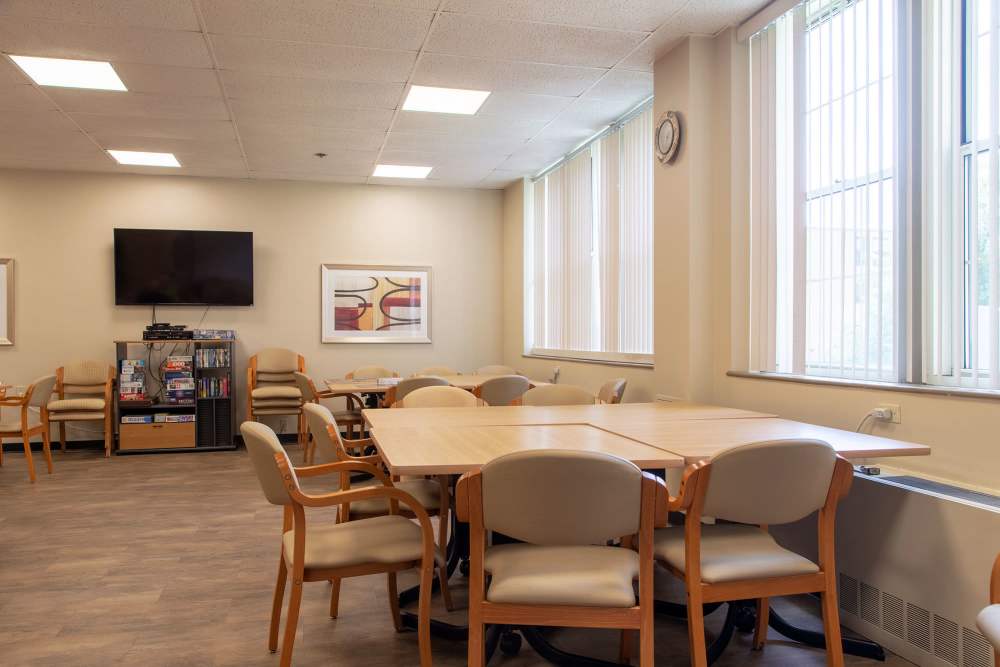 community room with tables and a large TV at Fairhaven Village in Fairhaven, Massachusetts