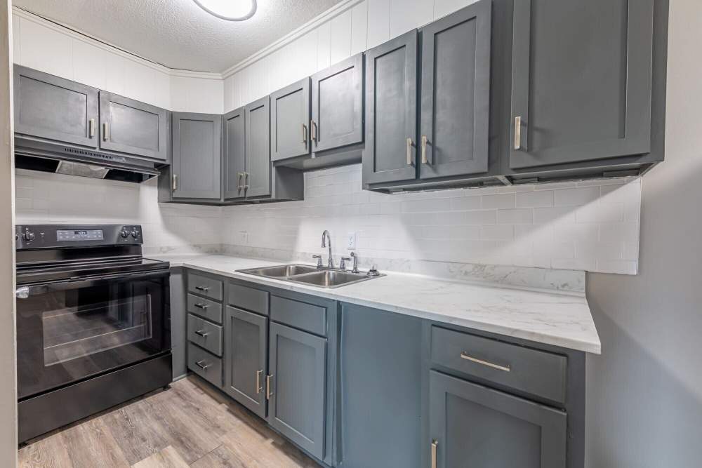Kitchen with black appliances and wooden floorling at Lofts At Glenhaven in Winston Salem, North Carolina