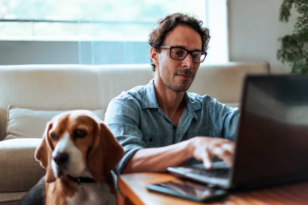 Resident working in his laptop with his pet dog at Branch Creek Apartments in Carrollton, Texas