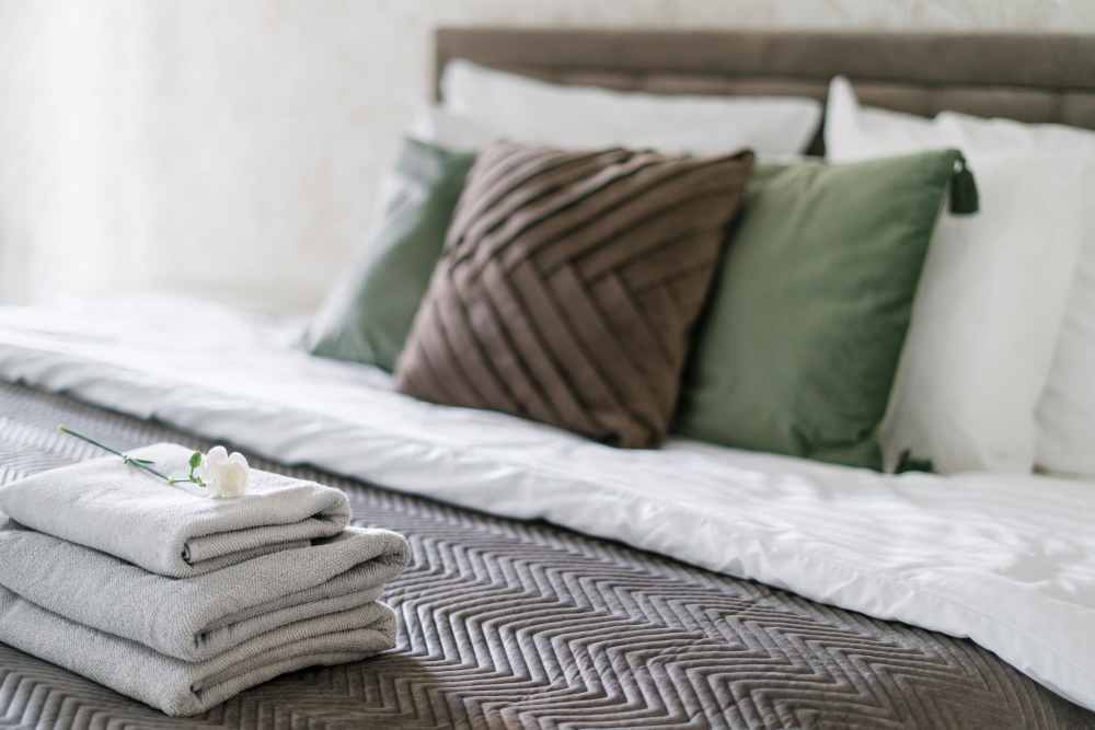 Cozy bedroom with plush pillows and towels at Apperson Way Apartments in Kokomo, Indiana