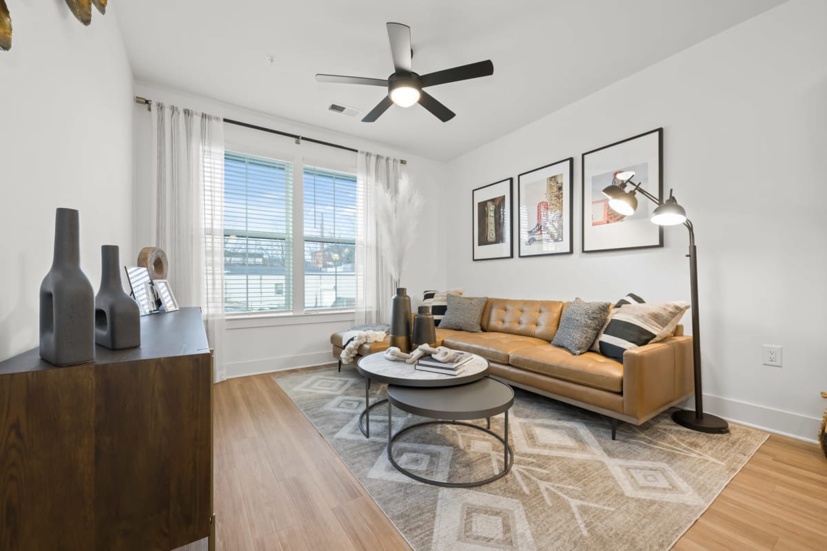 Living room with hardwood-style flooring and a large window at The Scottie in Nashville, Tennessee  