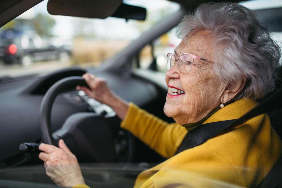 Elderly woman driving in a car, wearing a yellow jacket at Villas At Meadow Springs in Ankeny, Iowa