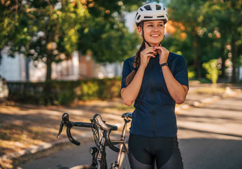 Resident wearing a helmet standing with a bicycle on a tree-lined path near Unionville Station Townhomes in Hilton, New York