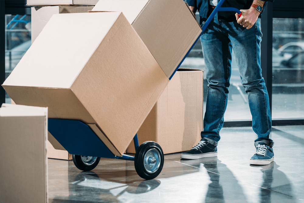 Man pushing dolly loaded with boxes at A-American Self Storage in Lancaster, California