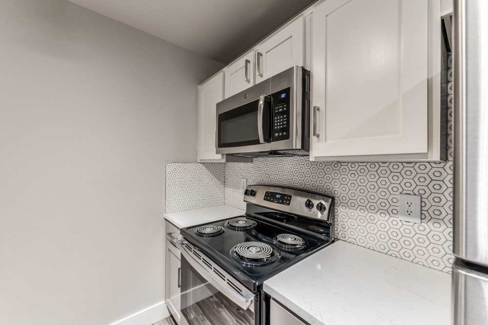 Kitchen with steel appliances and white cabinets at Warwick at Westchase in Houston, Texas
