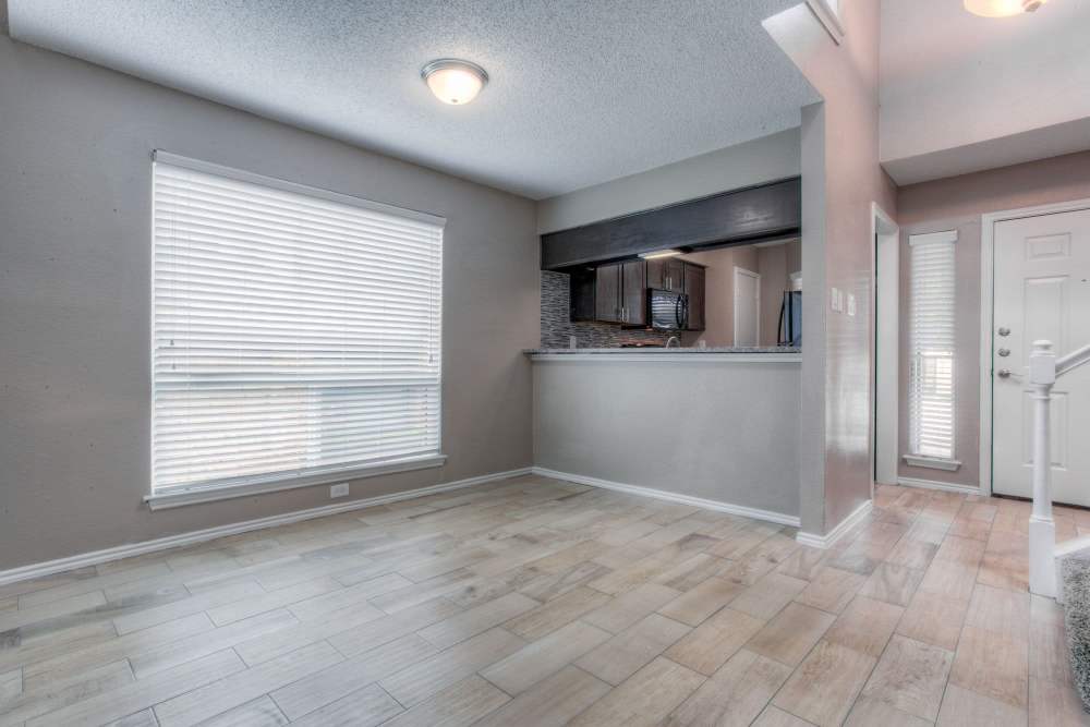 Unfurnished living with large windows and showing kitchen at The Quorum At Trophy Club in Trophy Club, Texas