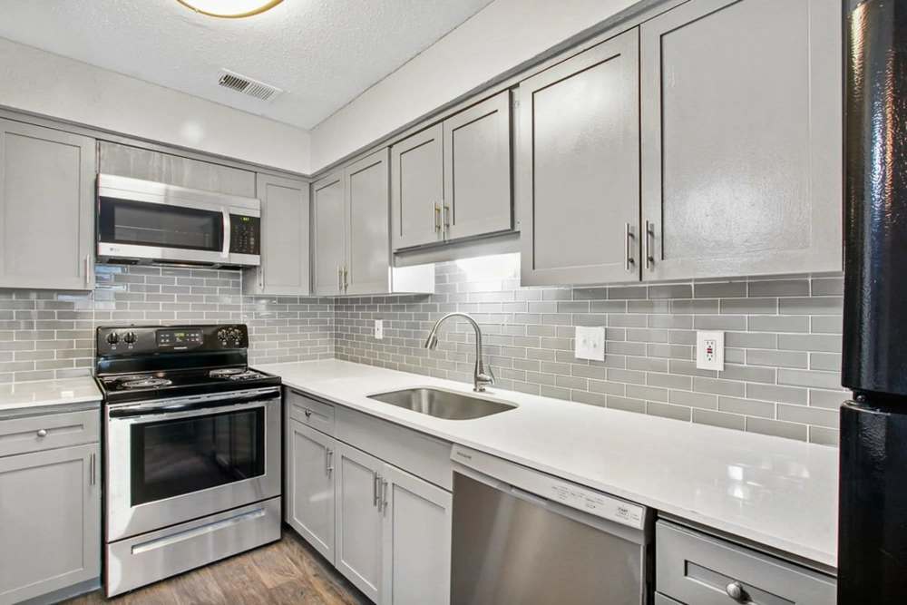 Cozy apartment kitchen with stainless-steel appliances including dishwasher and microwave at Parkwyn Townhomes in North Richland Hills, Texas
