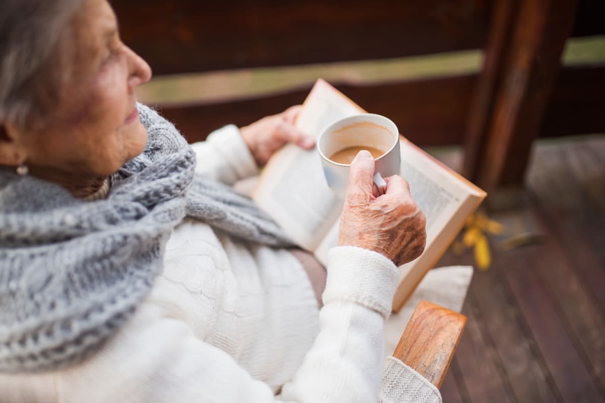 A resident enjoying tea and a good book at The Oxford Grand Assisted Living & Memory Care in Wichita, Kansas