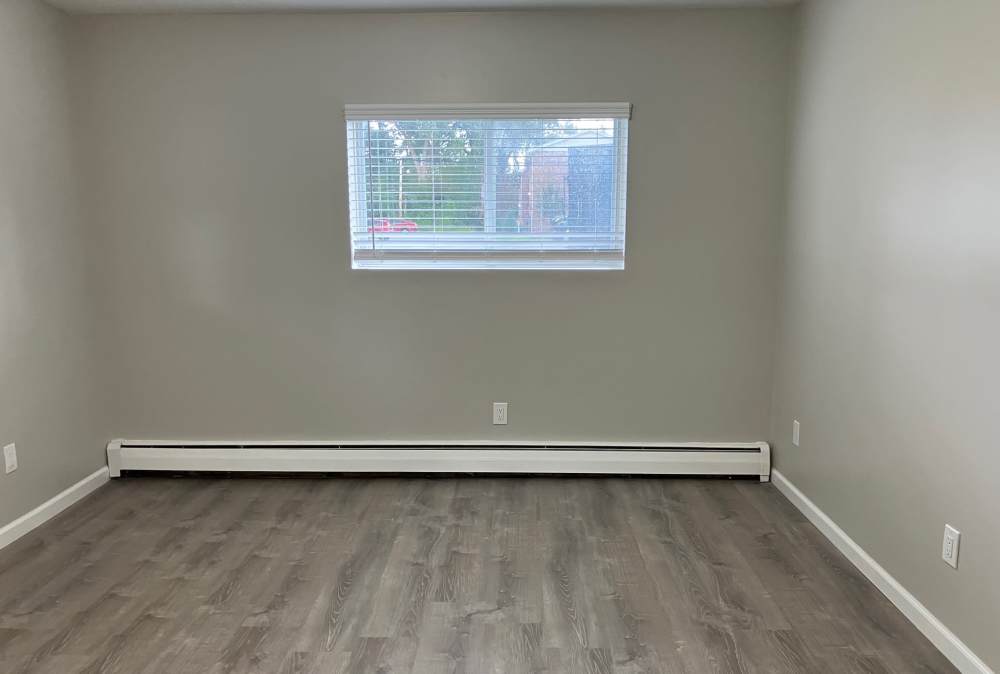 Bedroom with wood flooring and window at Country Manor Apartment Homes in Webster. NY