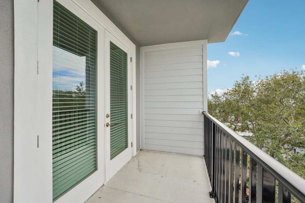 Small balcony with French doors, black railing, and tree view at Jade at North Hyde Park in Tampa, Florida