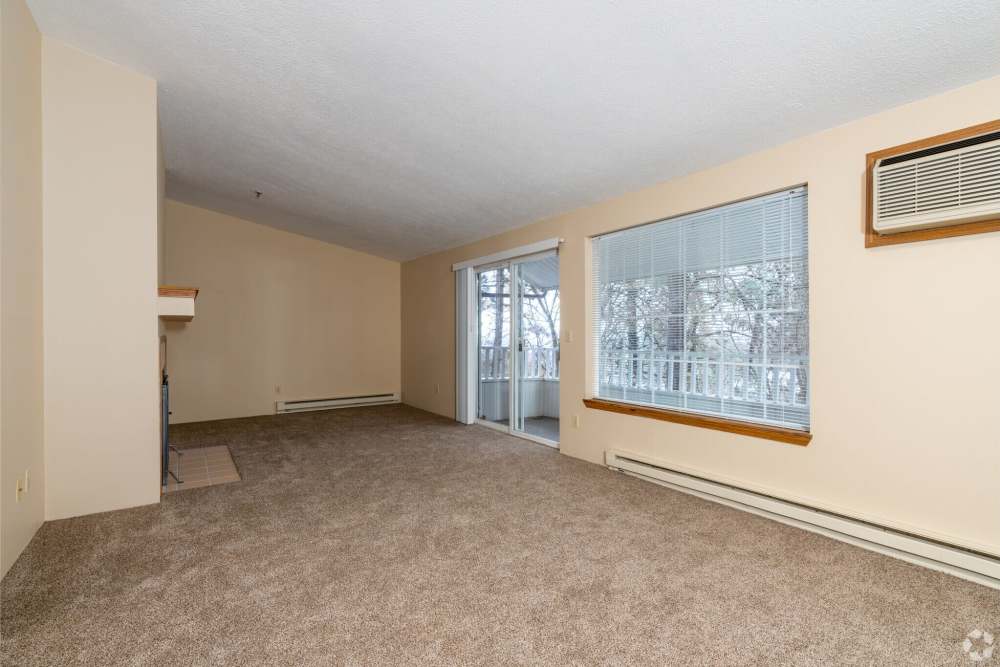Unfurnished living room with large window, sliding glass door to balcony and baseboard heaters at Stonecrest Apartments in Spokane, Washington