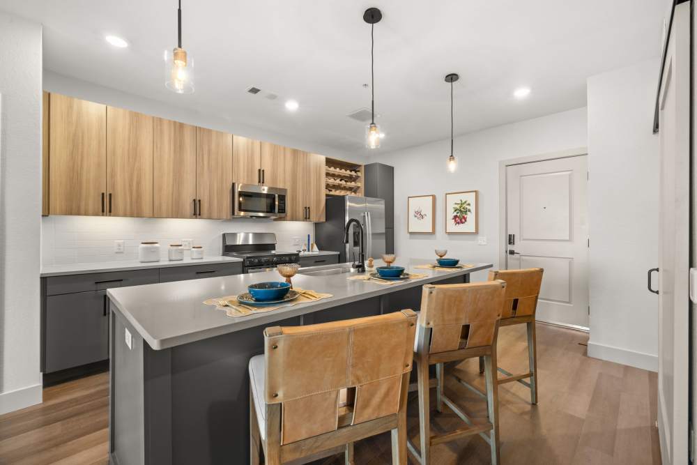 Bar seating at the kitchen island with stainless-steel in a model home at The Lock at Flatirons in Broomfield, Colorado