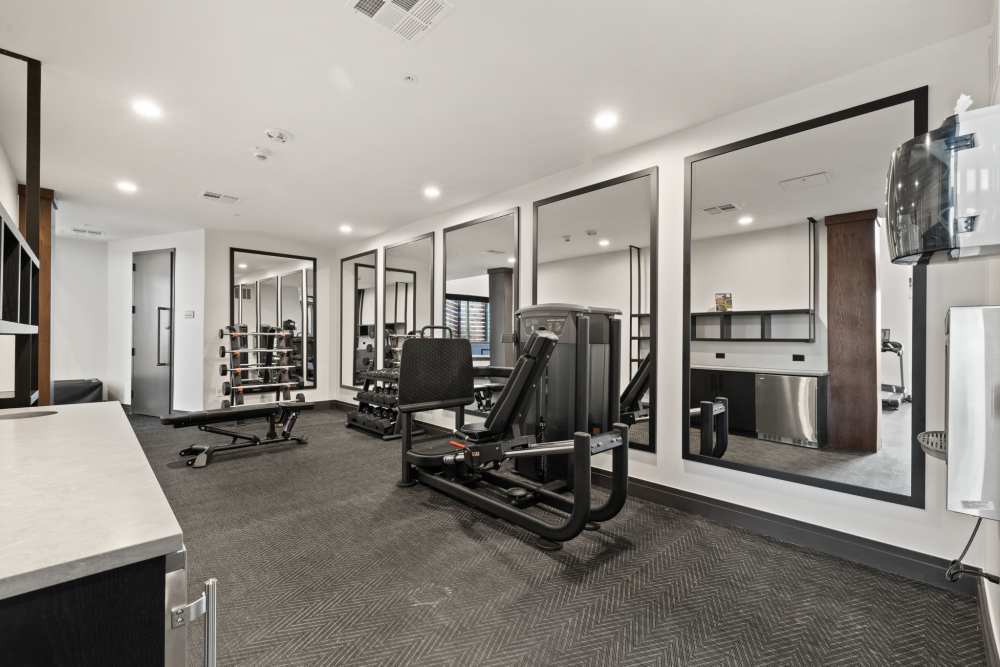 A weight machine and a collection of dumbbells in a well-equipped fitness center at The Lock at Flatirons in Broomfield, Colorado