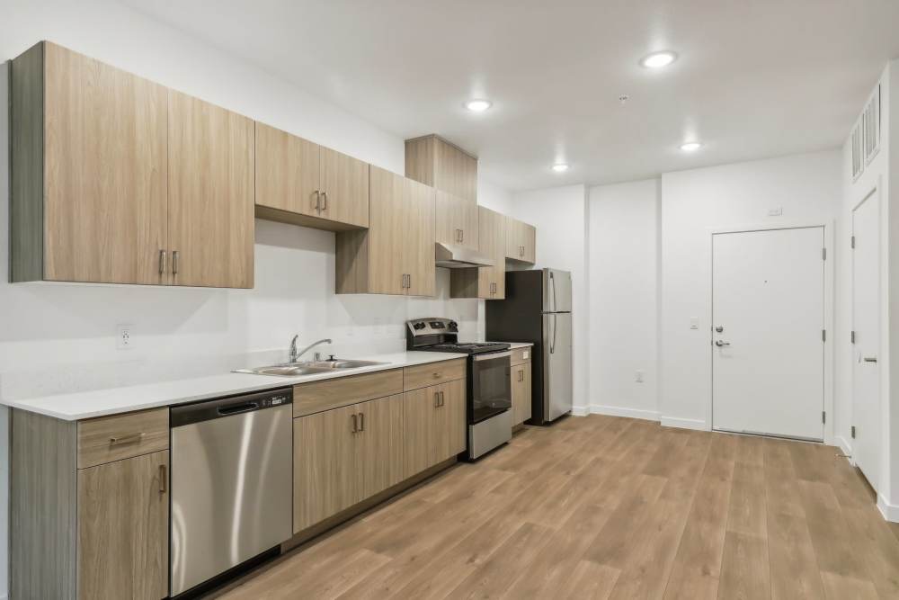 Kitchen with range, dishwasher and wooden cabinets at Tempo in Las Vegas Nevada