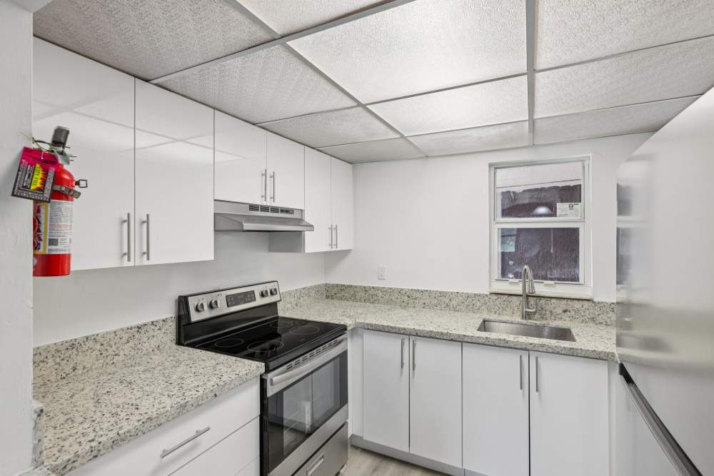 Granite countertops and white cabinets in kitchen at El Jardin Apartments in Hollywood, Florida