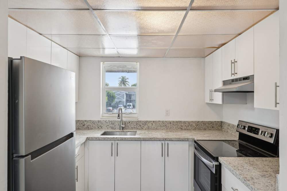 Well-equipped kitchen with granite countertops at El Jardin Apartments in Hollywood, Florida