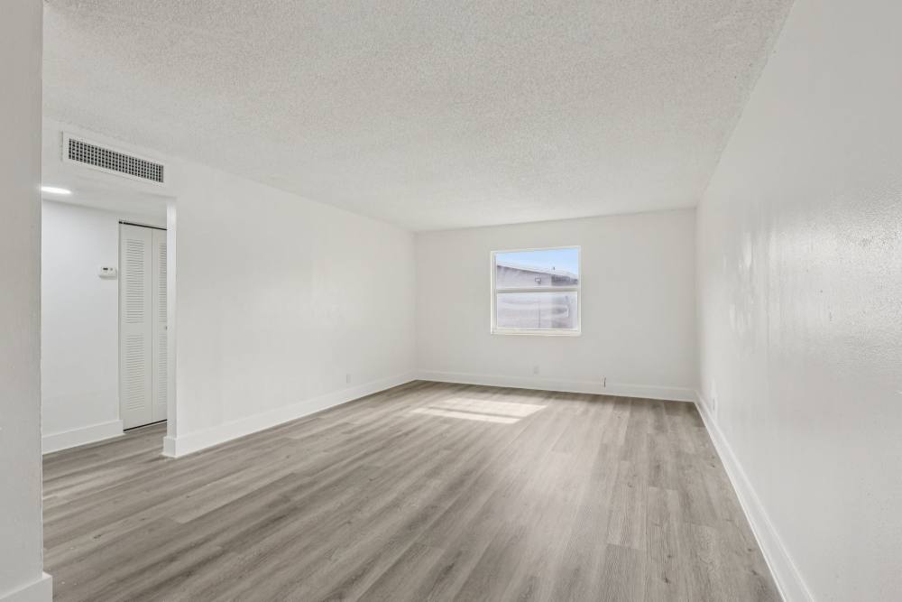 Well-lit living area with wood style flooring at El Jardin Apartments in Hollywood, Florida