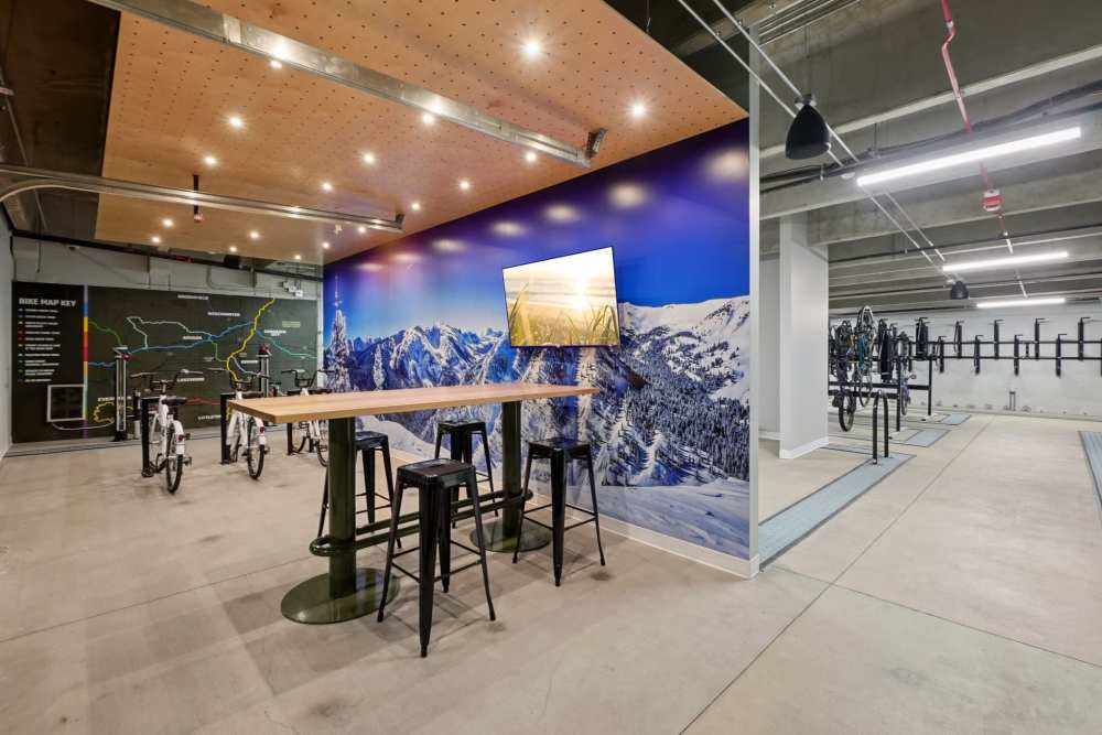 Indoor bike area with map, mountain mural, and high table with stools at Tempo at Nine Mile Station in Aurora, Colorado
