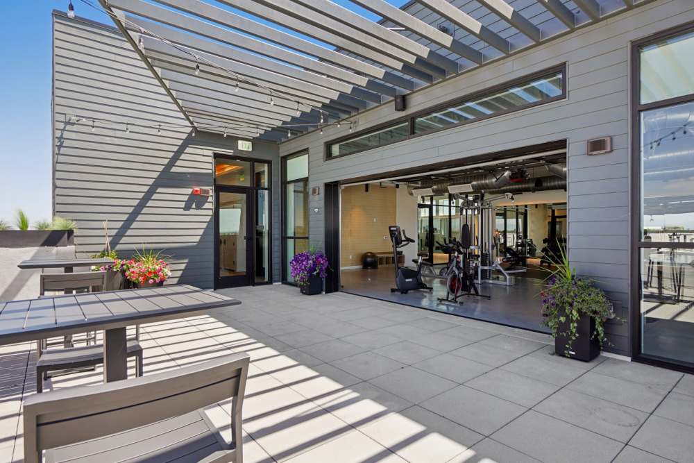 Outdoor patio near gym with tables, plants, and pergola at Tempo at Nine Mile Station in Aurora, Colorado