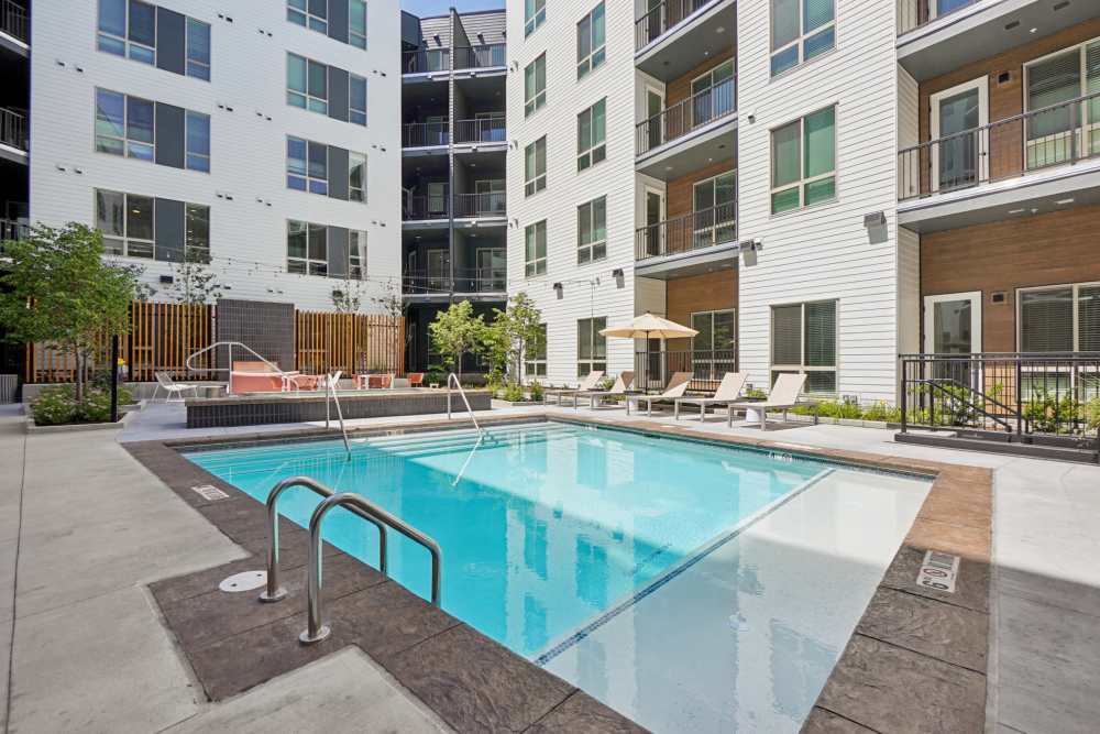 Apartment complex with pool, lounge chairs, and balconies at Tempo at Nine Mile Station in Aurora, Colorado