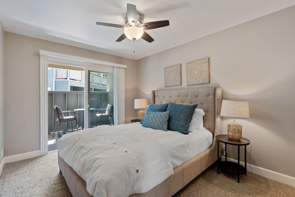 Bedroom with plush carpeting and a ceiling fan opening onto a private balcony at Pinebrook Apartments in Fremont, California