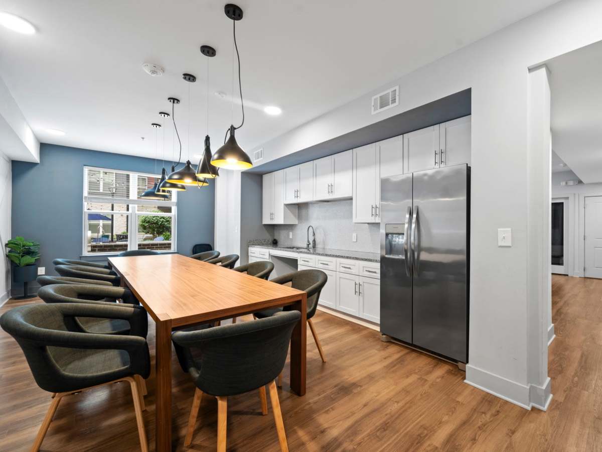 Community kitchen with stainless-steel appliances, large dining table and chairs at The Rise at Regency in Henrico, Virginia