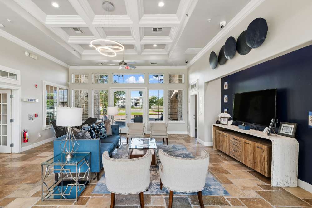 Well-furnished resident clubhouse lounge area with armchairs, a blue sofa, and a flatscreen TV at Residence at Lake Jackson in Lake Jackson, Texas