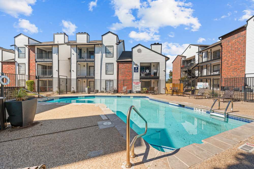 Resort-style pool surrounded by lounge chairs and apartment buildings with balconies at The Fielder in Austin, Texas