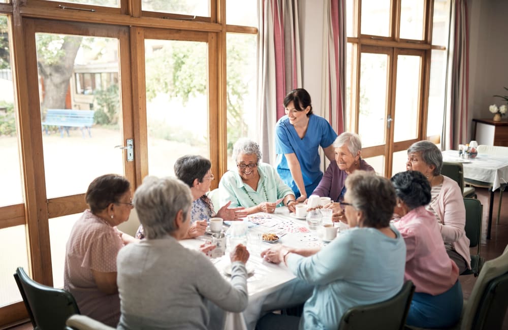 A caretaker enjoying a laugh with residents as they play a game of cards at Amira in Bloomington, Minnesota
