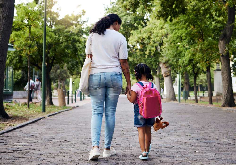 Mother and child walking through a lush green park at Messina Luxury Apartments in New Smyrna Beach, Florida